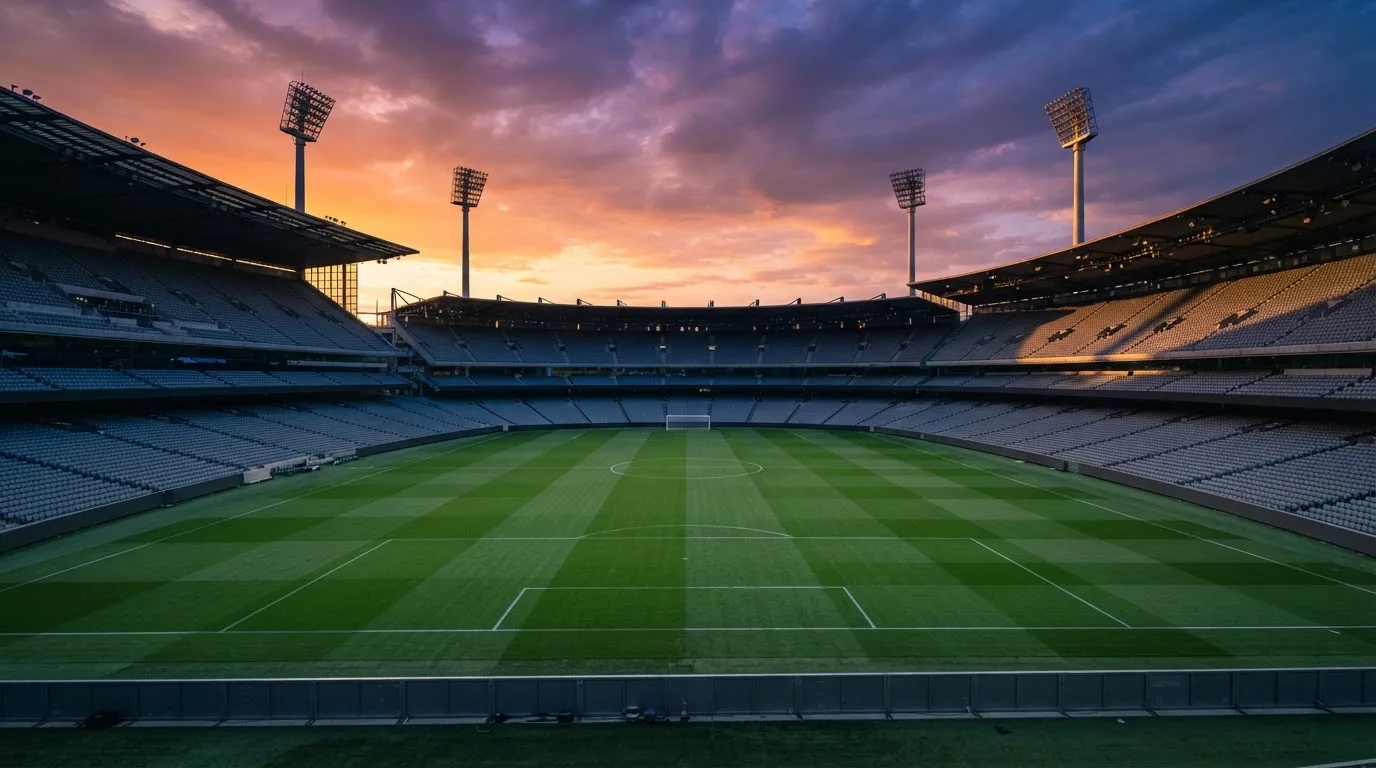 Un estadio de fútbol vacío con torres de iluminación al atardecer