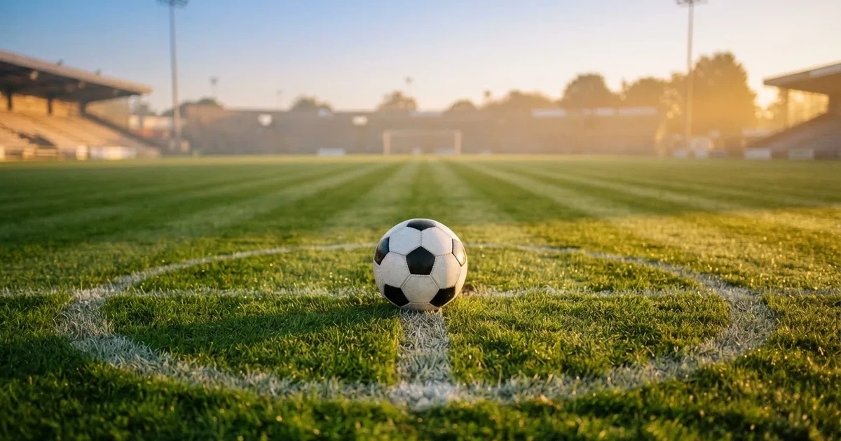 Un balón en el punto central de un campo de césped a la luz de la mañana