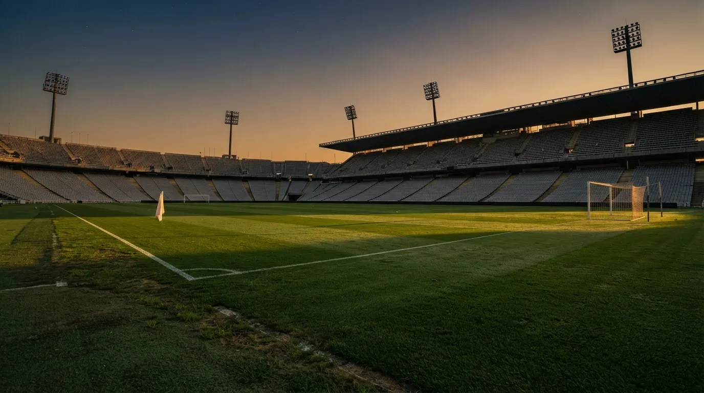 Un estadio de fútbol vacío con torres de iluminación al atardecer