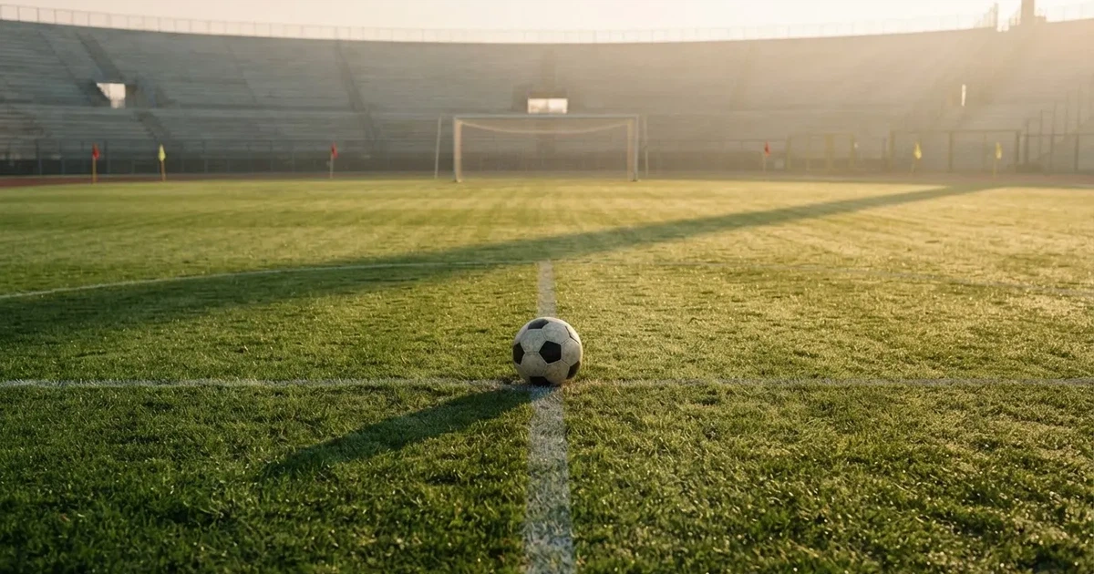 Un balón en el punto central de un campo de césped a la luz de la mañana
